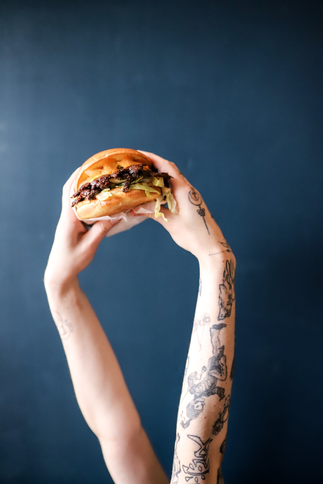 Hands holding the Hanks signature burger, lettuce falling