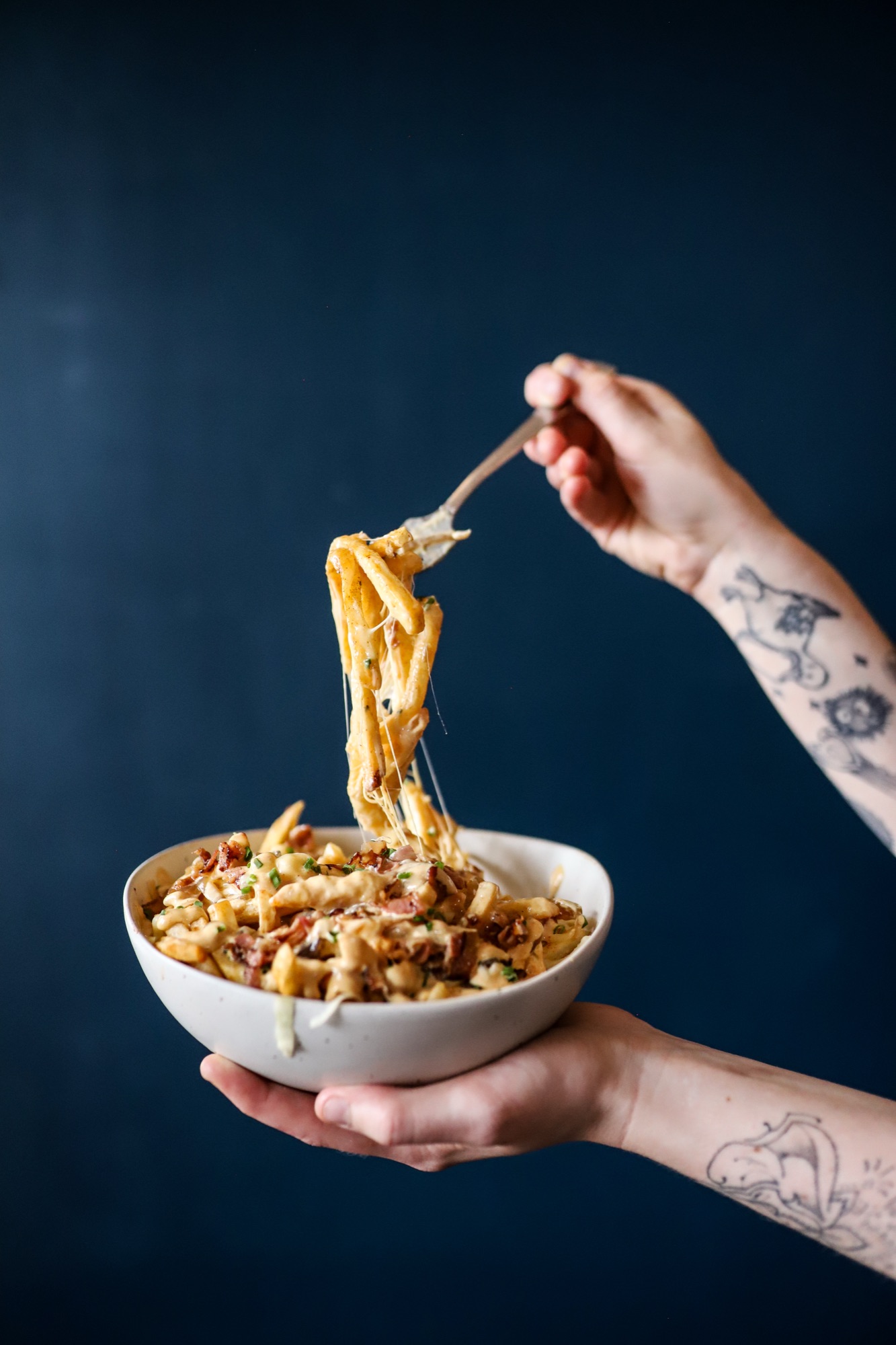 Cheese fries with a cheese pull on a fork